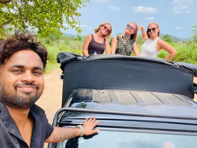 A man taking a selfie with three women smiling from the back of a jeep.